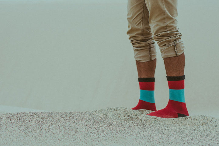 Man wearing red and green socks in the sand